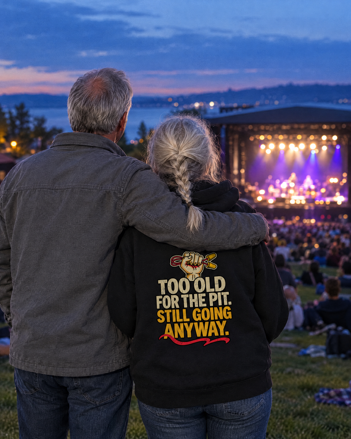 Couple watching an outdoor amphitheatre show, she wears the Too Old for the Pit hoodie