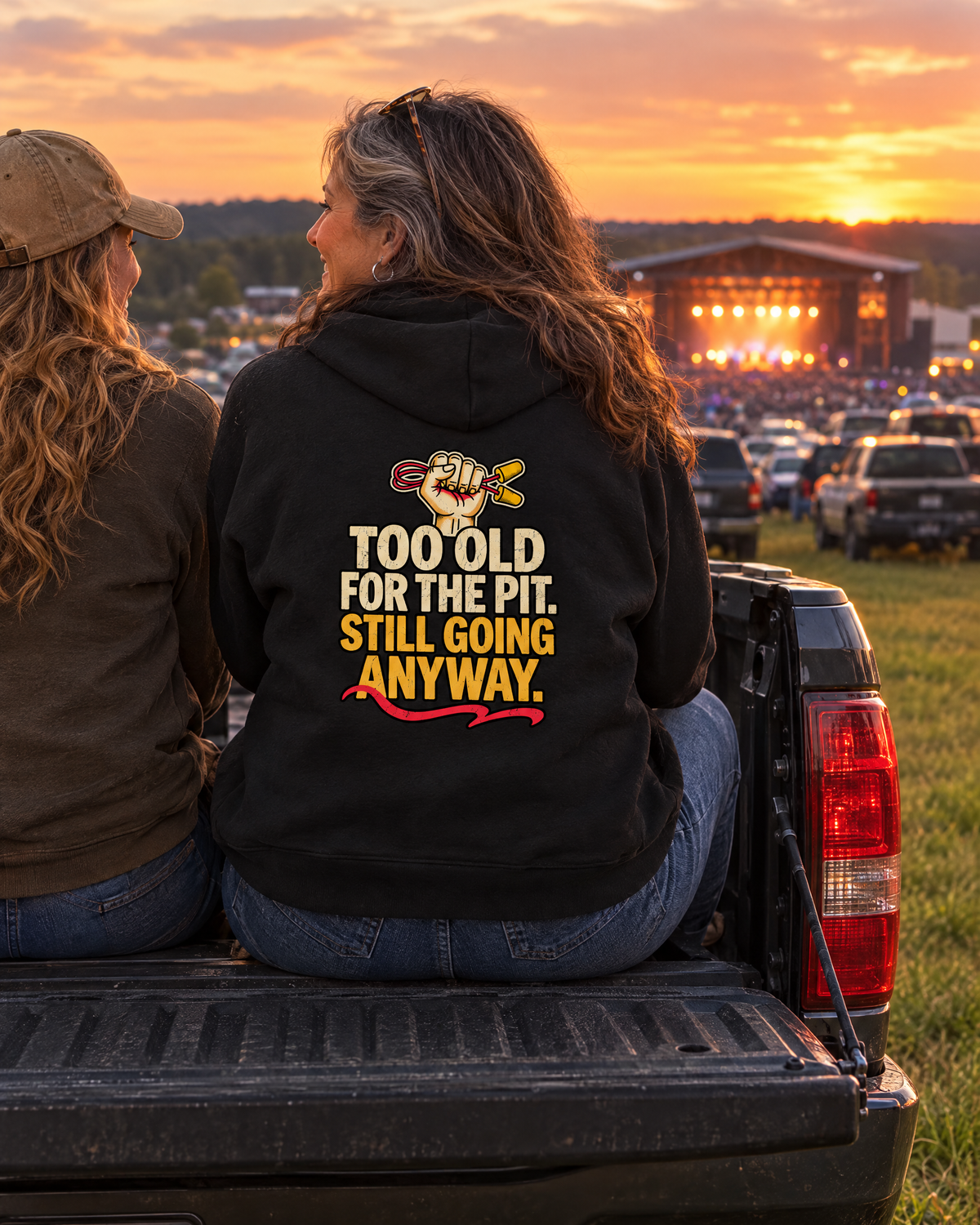 Friends on a truck tailgate after an outdoor show, one in the Too Old for the Pit hoodie